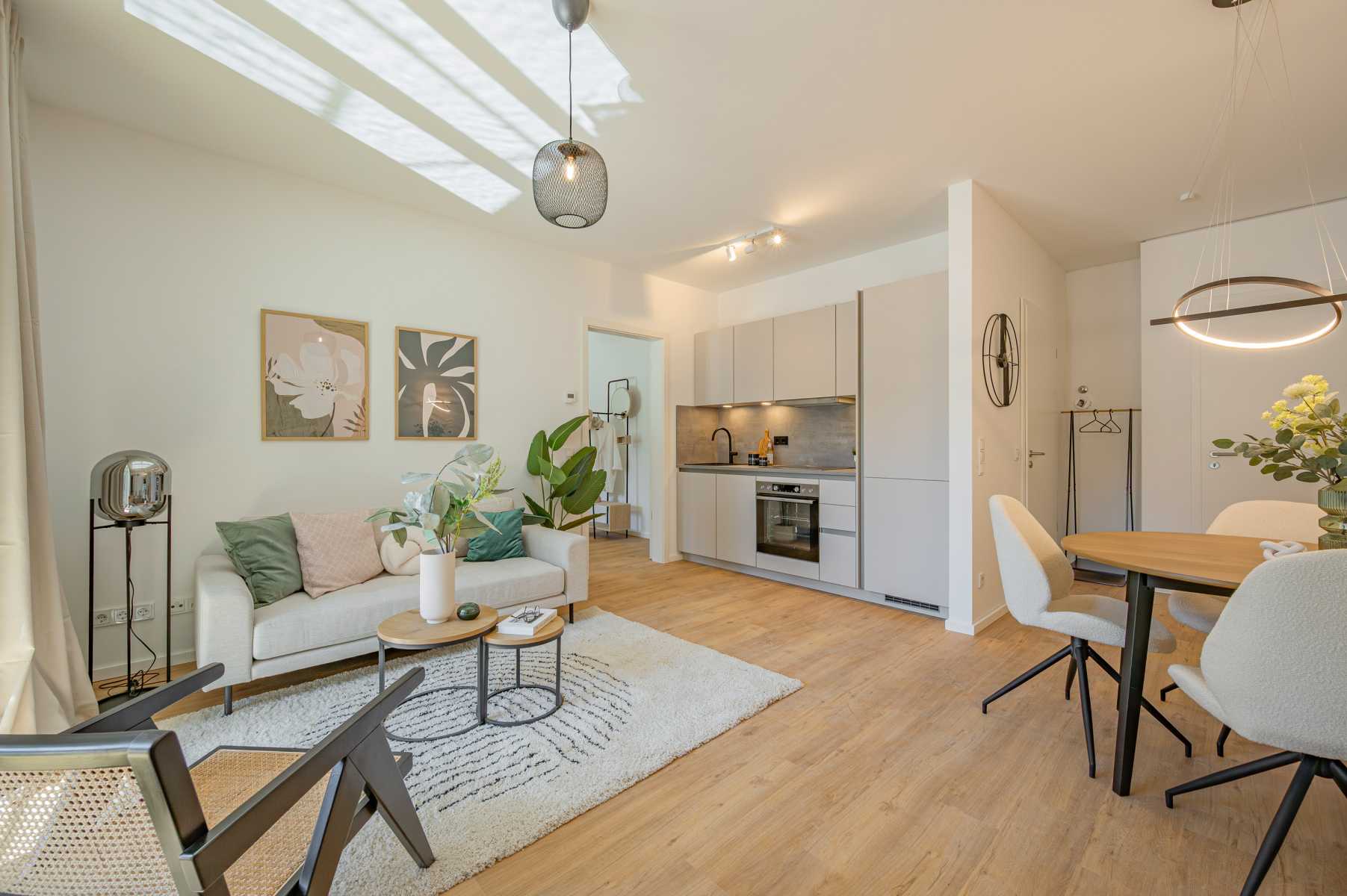 Helles, modernes Wohnzimmer mit offener Küche, Esstisch und gemütlichem Sofa.