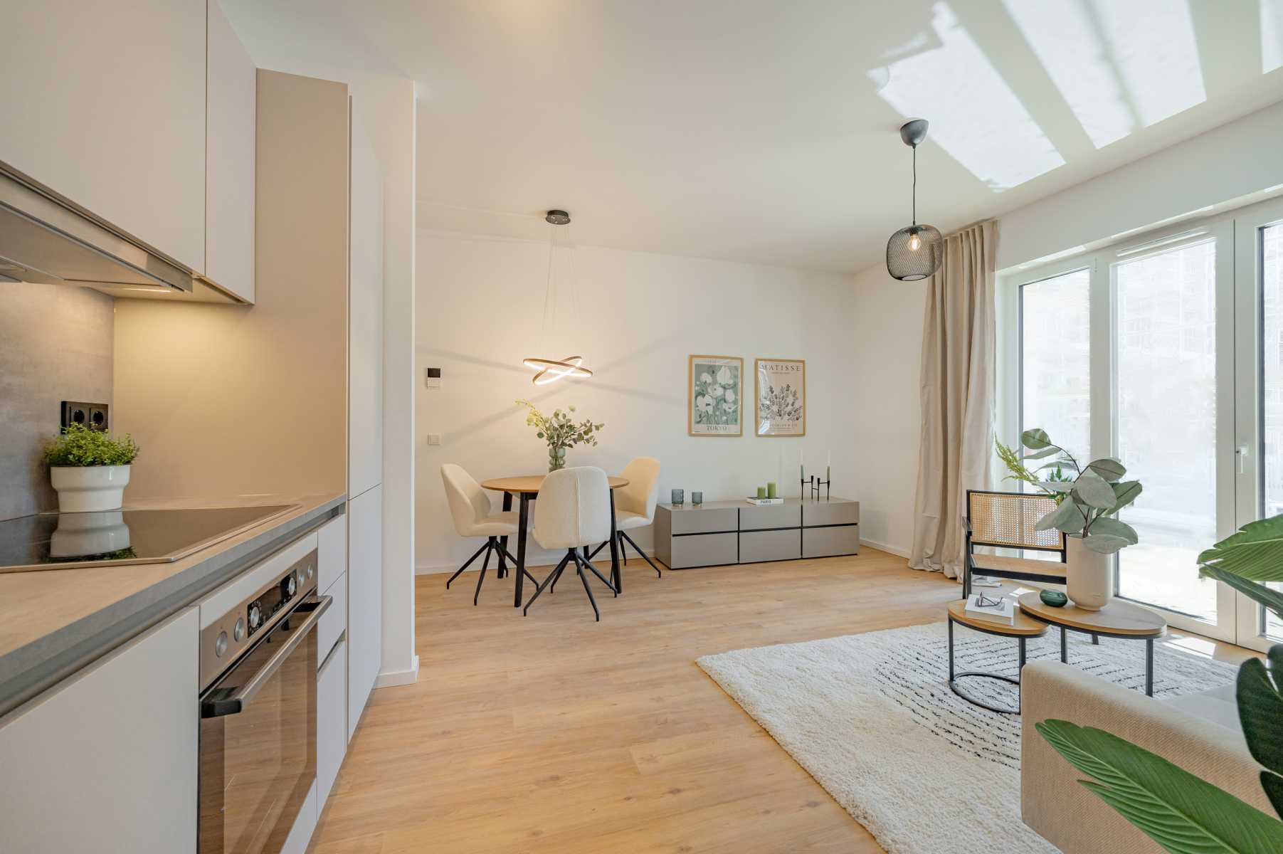 Helles, modernes Wohn-Esszimmer mit offener Küche und großen Fenstern.