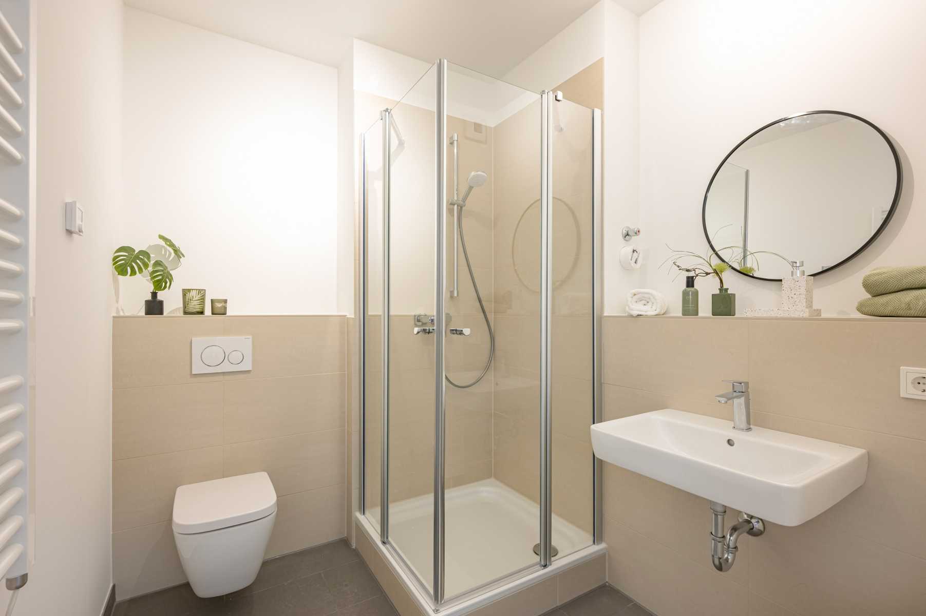 Modernes Bad mit Dusche, WC, Waschbecken, Spiegel und grünen Dekopflanzen.