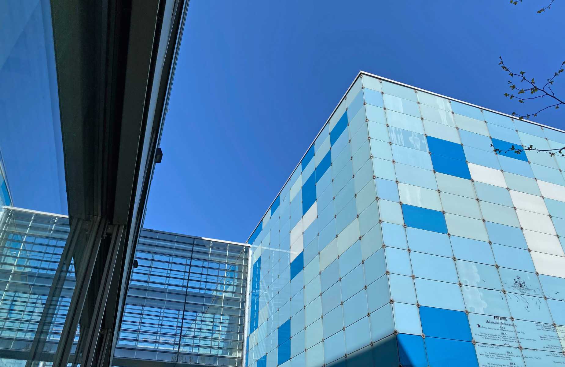 Moderne Gebäude mit blauer Glasfassade vor klarem, wolkenlosem Himmel.