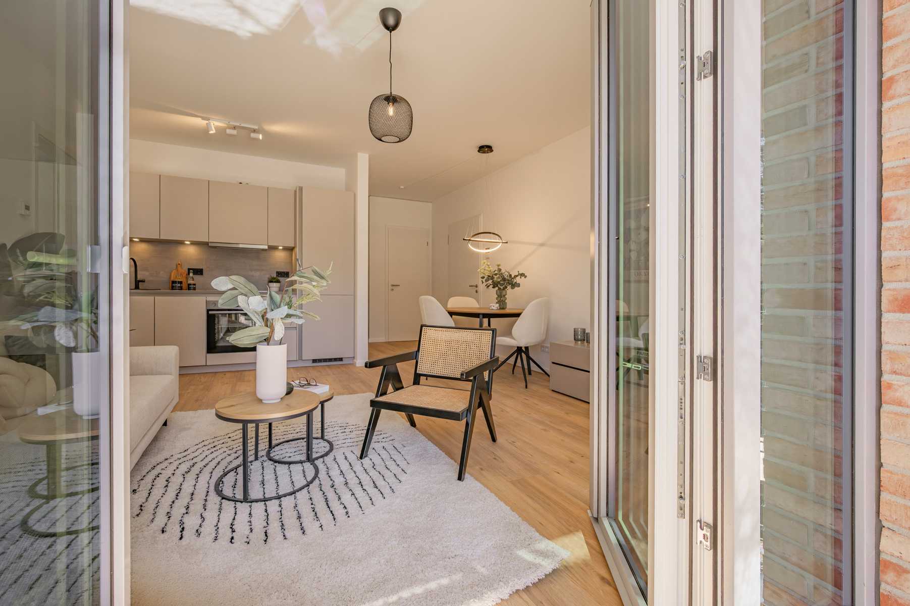 Helles, modernes Wohnzimmer mit Küche, Essbereich und Holzboden, von Balkon aus.