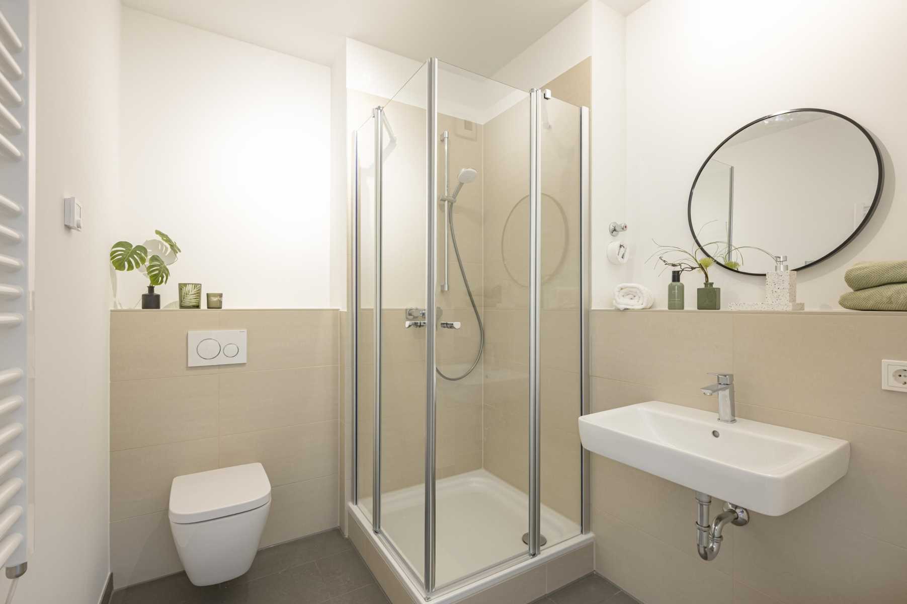 Modernes, helles Badezimmer mit Dusche, WC, Waschbecken und Deko-Pflanzen.
