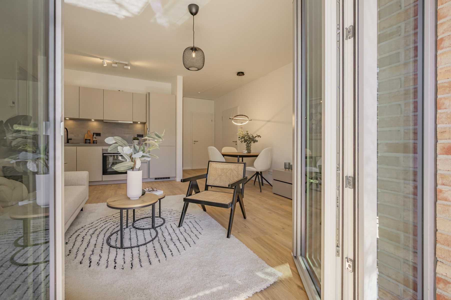 Helles Wohnzimmer mit Küche, Esstisch und moderner Einrichtung, Blick von außen.